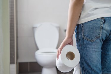 Midsection Of Woman Holding Toilet Paper While Standing In Bathroom, as a concept of a burning sensation after urinating