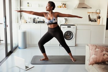 Black woman practicing yoga in a sun-lit room in her home