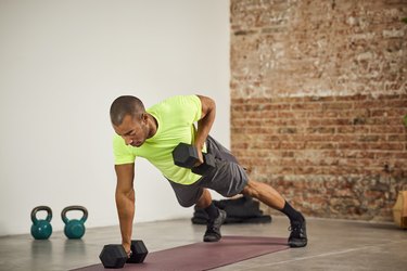 Person performing a dumbbell renegade row as part of a 20-minute dumbbell back workout.