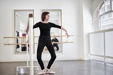 Senior woman exercising at barre in a ballet studio