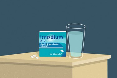An illustration of a package of imodium for diarrhea on a table next to a glass of water and two white capsules
