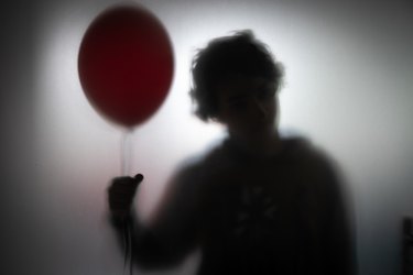a spooky silhouette of a person holding a balloon, to represent the psychological effects of watching horror movies