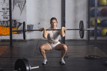 woman doing a barbell front squat at the gym