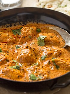 A savory pan of Chicken Tikka Masala with a large spoon