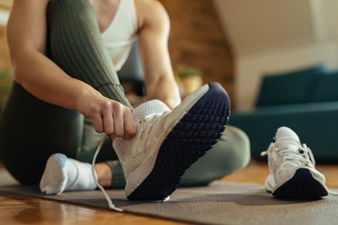 Close-up of athletic woman with athlete's foot putting on sneakers