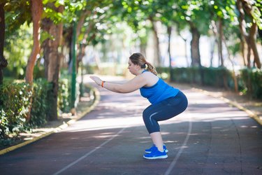 Woman doing a squat workout in park