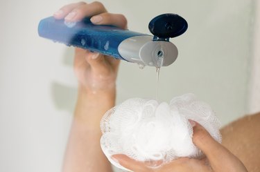 Close up of person pouring shower gel on puff.
