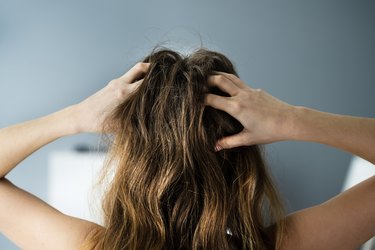 back view of a person with long hair itching their scalp