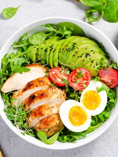 A salad bowl consisting of grilled chicken, avocado, tomatoes and hard boiled eggs