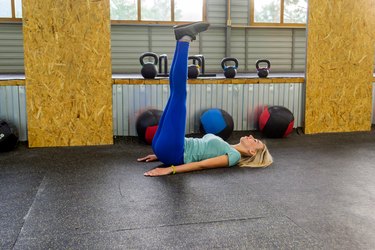 blonde woman wearing blue leggings and doing leg raise ab exercise