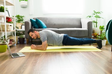 person doing plank hip dips on a yellow exercise mat in a living room