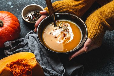 Female hands with bowl of high protein pumpkin soup